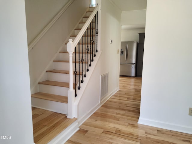 stairs featuring hardwood / wood-style floors and crown molding