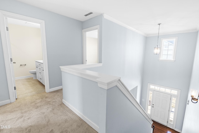 carpeted foyer featuring a chandelier and crown molding