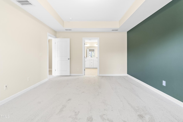 carpeted spare room with a raised ceiling