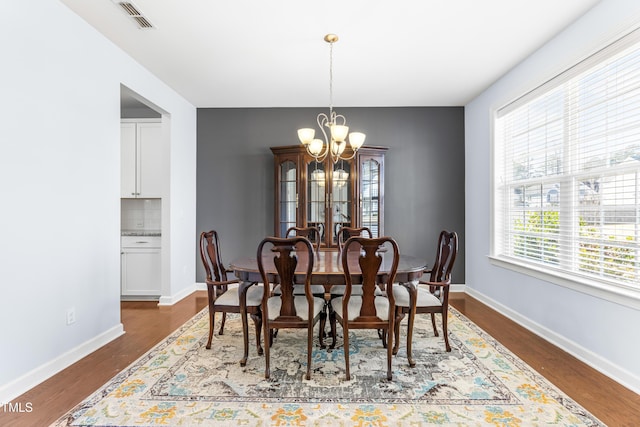 dining room with dark hardwood / wood-style flooring and an inviting chandelier