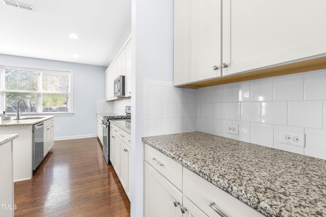 kitchen with white cabinets, sink, light stone countertops, tasteful backsplash, and stainless steel appliances