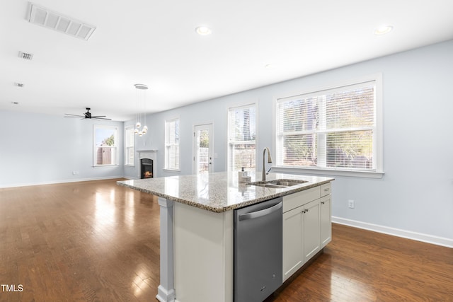 kitchen with dishwasher, a center island with sink, white cabinets, sink, and light stone counters