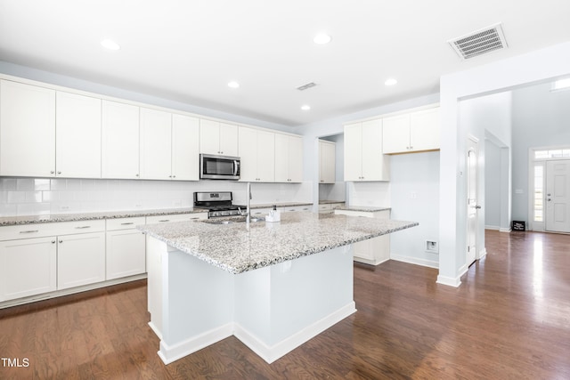 kitchen with light stone countertops, white cabinetry, an island with sink, and stainless steel appliances