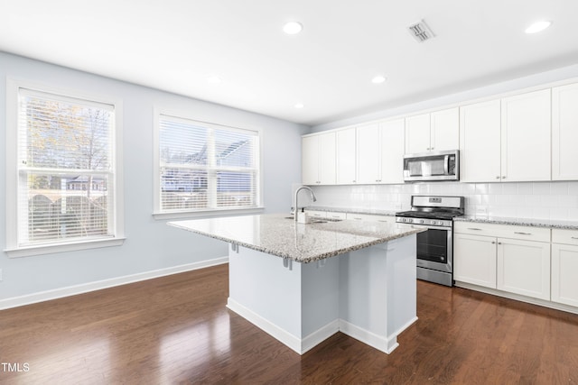 kitchen featuring white cabinetry, sink, stainless steel appliances, tasteful backsplash, and a center island with sink