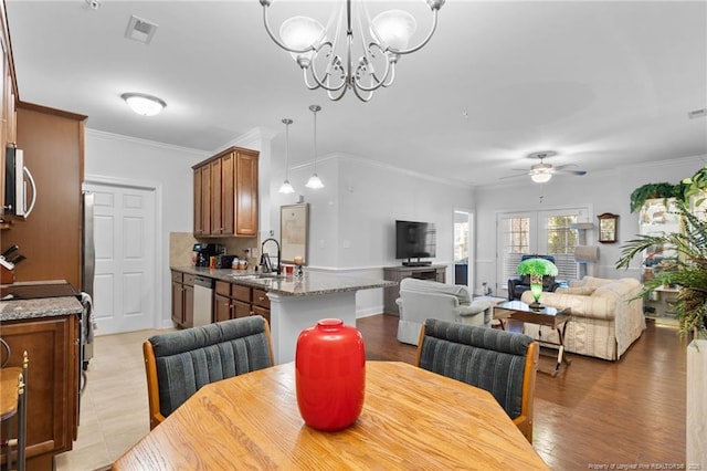 dining room featuring ceiling fan with notable chandelier, ornamental molding, and sink