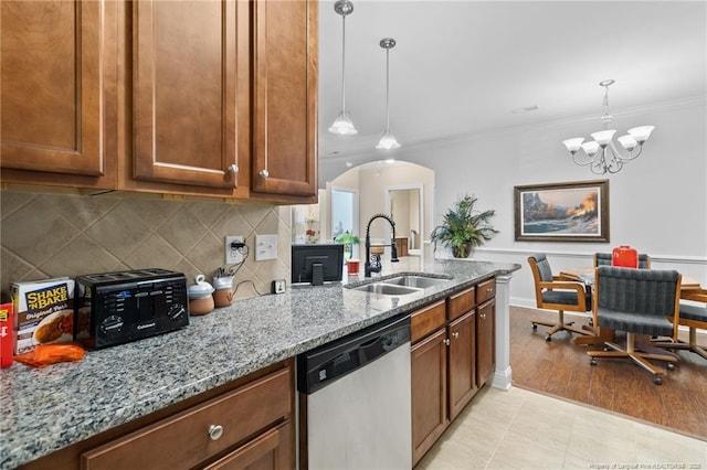 kitchen featuring light stone countertops, dishwasher, sink, an inviting chandelier, and pendant lighting