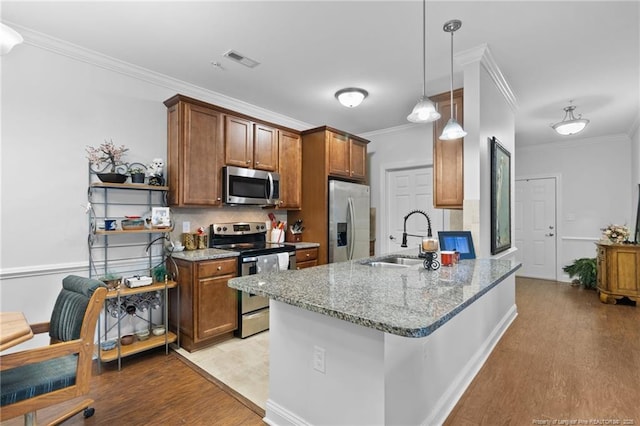 kitchen featuring light stone countertops, appliances with stainless steel finishes, ornamental molding, sink, and decorative light fixtures