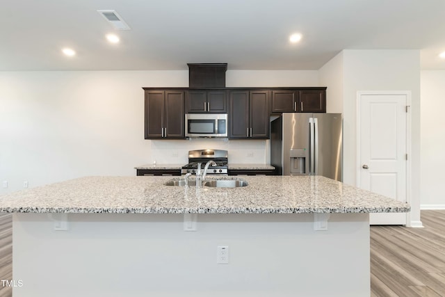 kitchen featuring a center island with sink, dark brown cabinetry, and stainless steel appliances