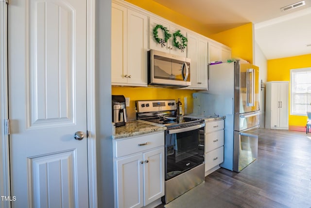 kitchen with lofted ceiling, light stone countertops, stainless steel appliances, and white cabinets