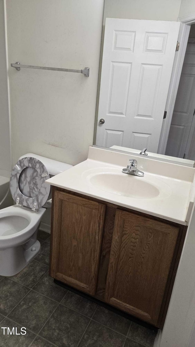 bathroom with toilet, vanity, and a bath