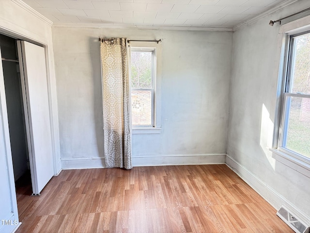 unfurnished room featuring a healthy amount of sunlight, light hardwood / wood-style floors, and ornamental molding