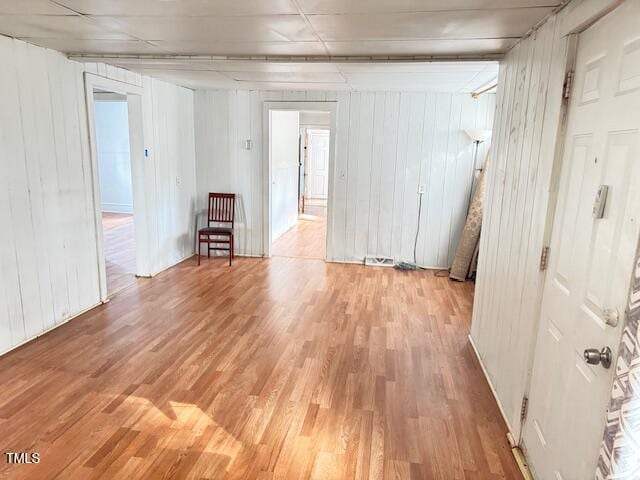 unfurnished room with wood walls and light hardwood / wood-style flooring