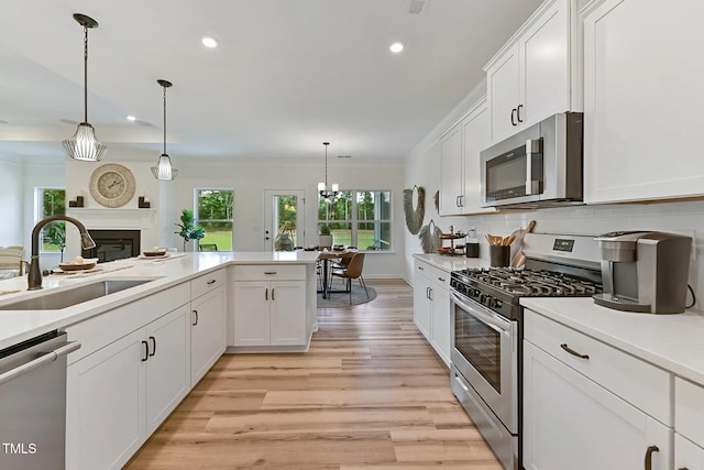 kitchen featuring tasteful backsplash, white cabinets, light wood-style flooring, appliances with stainless steel finishes, and a sink