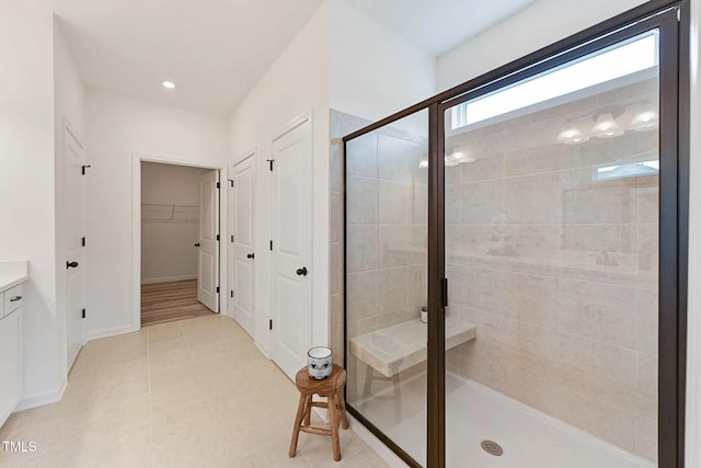 full bath featuring baseboards, a walk in closet, vanity, a shower stall, and recessed lighting