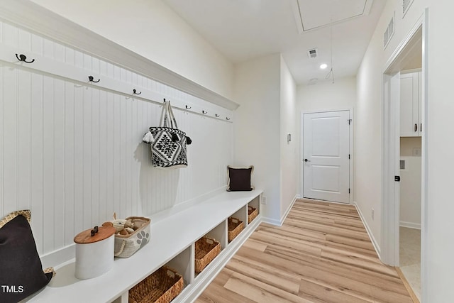 mudroom featuring attic access, visible vents, light wood-style flooring, and baseboards