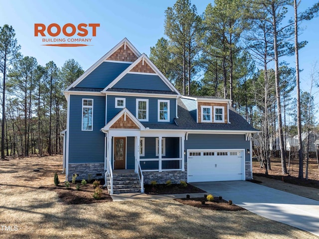 craftsman inspired home with a porch, concrete driveway, a garage, and roof with shingles