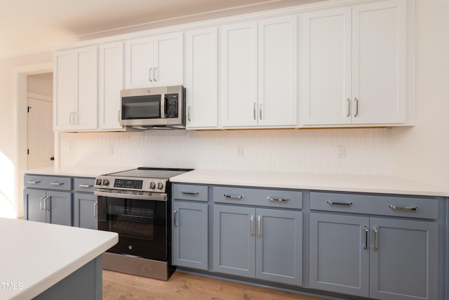 kitchen featuring light countertops, light wood-style flooring, gray cabinets, appliances with stainless steel finishes, and white cabinetry