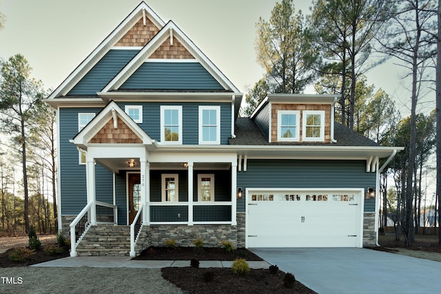 craftsman-style home with roof with shingles, covered porch, and driveway