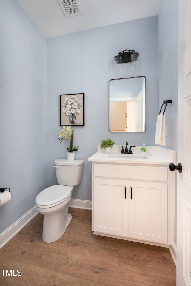 bathroom with visible vents, toilet, wood finished floors, baseboards, and vanity