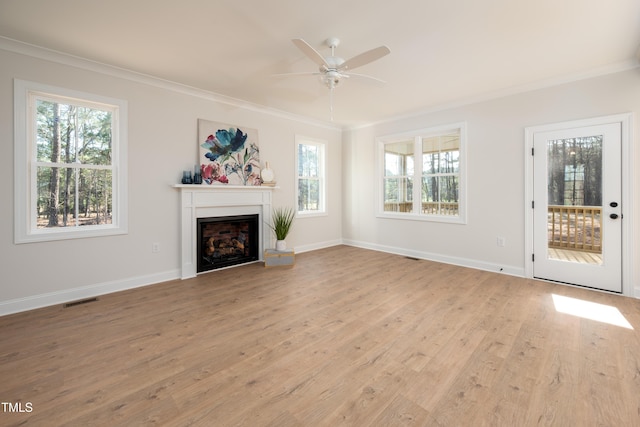 unfurnished living room with plenty of natural light, visible vents, and ornamental molding