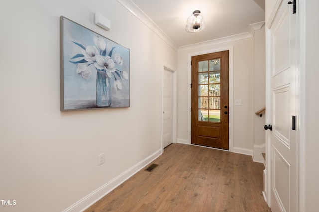 entryway with visible vents, baseboards, light wood-style flooring, and crown molding