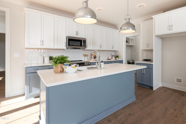 kitchen with a sink, stainless steel microwave, tasteful backsplash, and wood finished floors