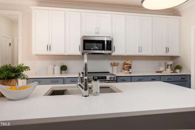 kitchen with stainless steel microwave, gray cabinetry, white cabinets, and light countertops