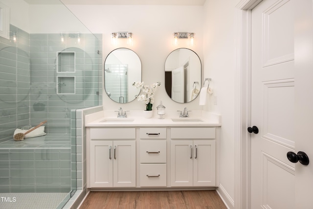 full bathroom with wood finished floors, tiled shower, and a sink