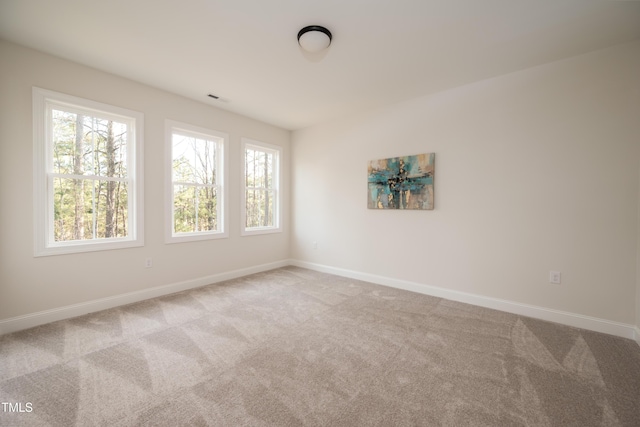 spare room featuring visible vents, carpet, and baseboards