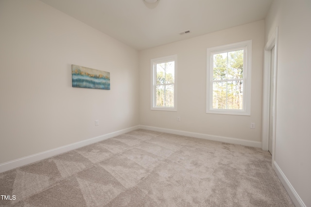 unfurnished room featuring visible vents, light colored carpet, and baseboards