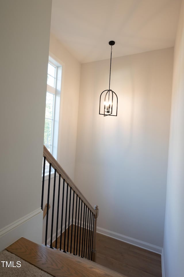 staircase with a notable chandelier, baseboards, and wood finished floors