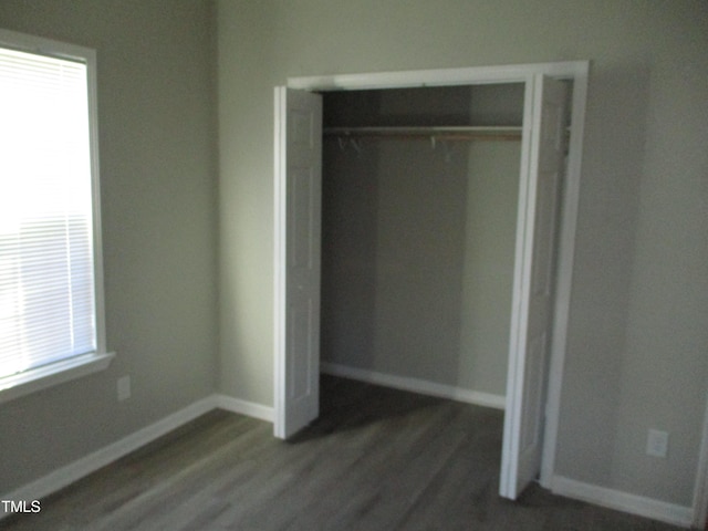 unfurnished bedroom with dark hardwood / wood-style flooring and a closet