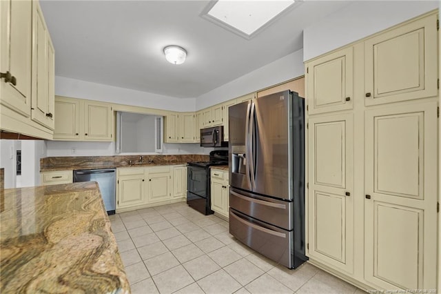 kitchen featuring light stone countertops, sink, black appliances, cream cabinets, and light tile patterned flooring