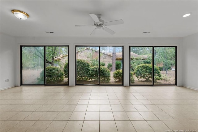 empty room with ceiling fan, light tile patterned floors, and a healthy amount of sunlight