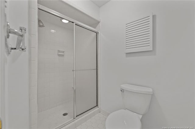 bathroom featuring toilet and a shower with shower door