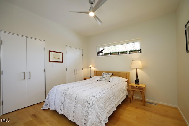 bedroom with ceiling fan, baseboards, multiple closets, and wood finished floors