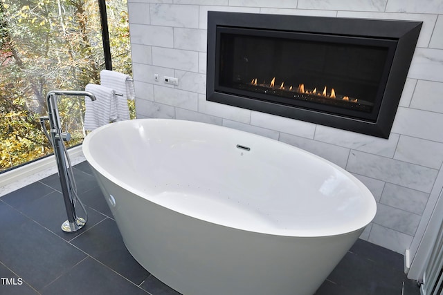 full bath featuring tile patterned floors, a soaking tub, tile walls, and a warm lit fireplace