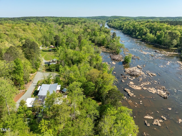 drone / aerial view with a wooded view and a water view