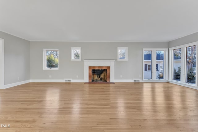 unfurnished living room featuring a brick fireplace and light hardwood / wood-style floors