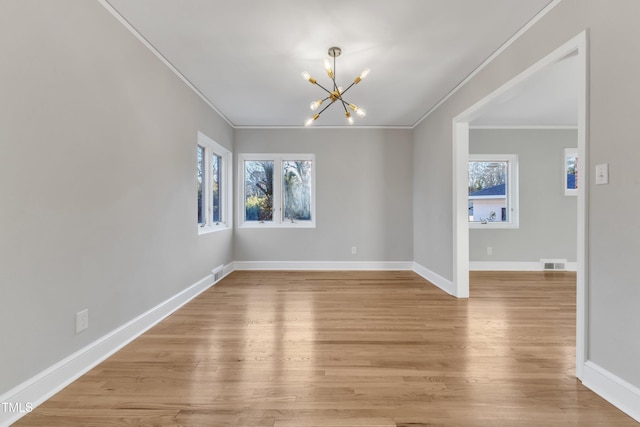 spare room featuring light hardwood / wood-style floors, ornamental molding, and an inviting chandelier