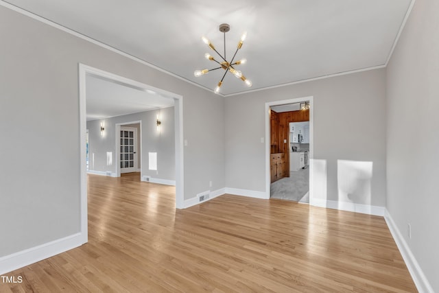 empty room with light wood-type flooring, ornamental molding, and a notable chandelier