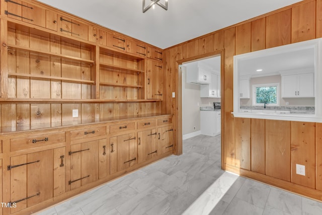 kitchen with sink, white cabinets, and wood walls