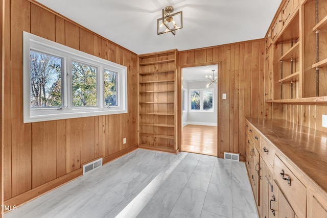 unfurnished dining area featuring crown molding, built in features, plenty of natural light, and an inviting chandelier