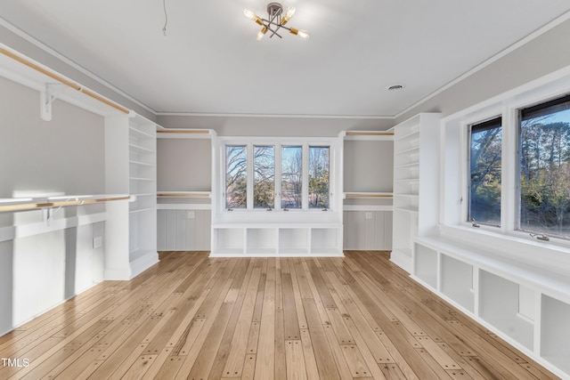 spacious closet featuring light wood-type flooring and a notable chandelier