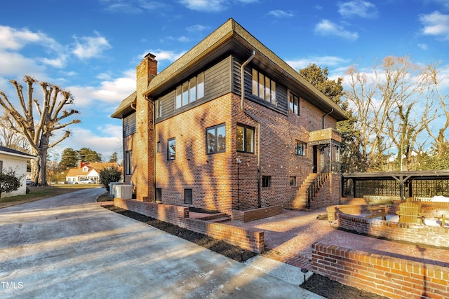 view of property exterior with a patio area, a fire pit, and central air condition unit