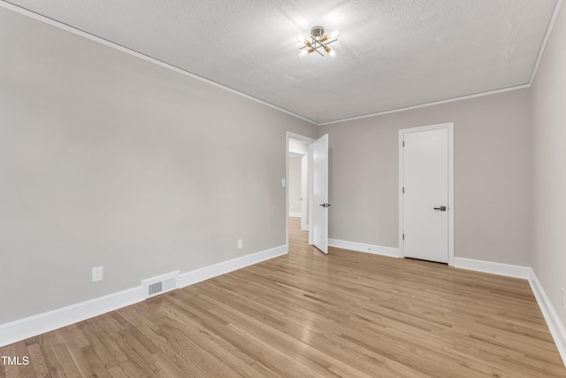 spare room featuring a textured ceiling, crown molding, and light wood-type flooring