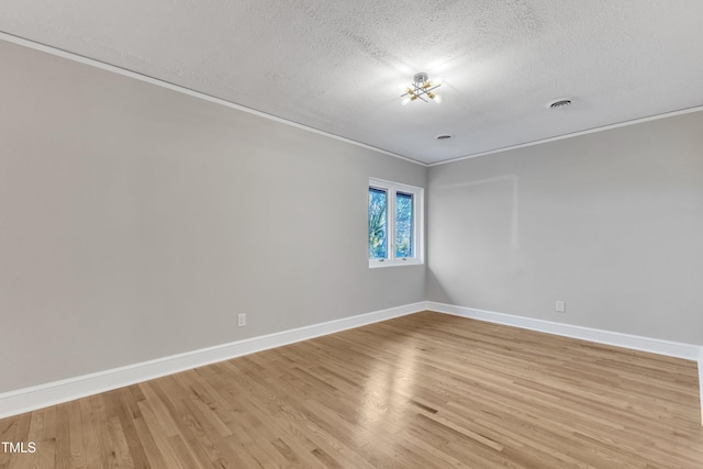 empty room featuring light wood-type flooring, a textured ceiling, and ornamental molding