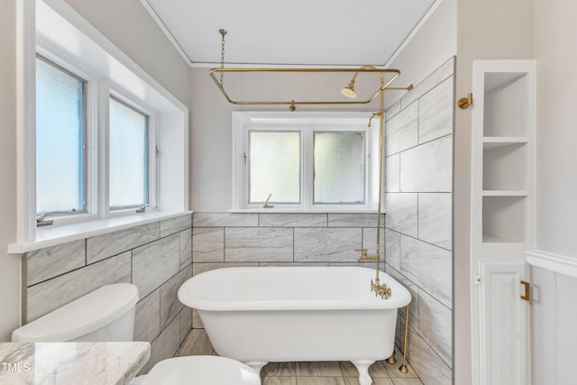 bathroom with toilet, tile walls, a tub, ornamental molding, and built in shelves