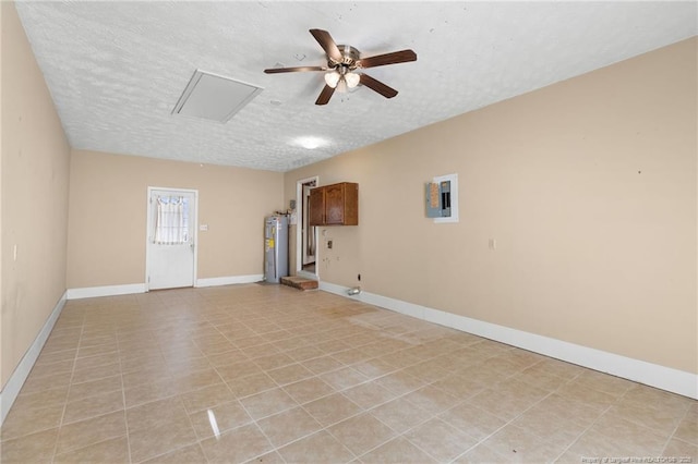 tiled spare room featuring a textured ceiling, electric panel, ceiling fan, and water heater