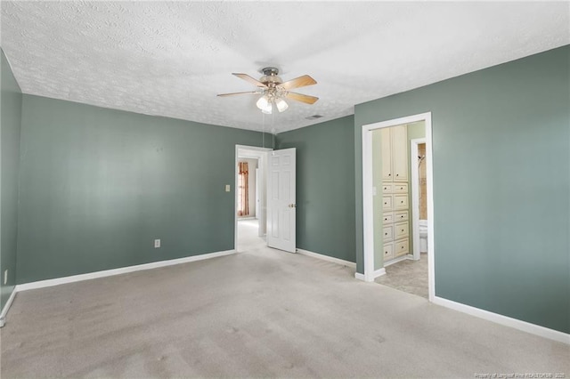 unfurnished bedroom featuring ensuite bathroom, ceiling fan, light colored carpet, and a textured ceiling